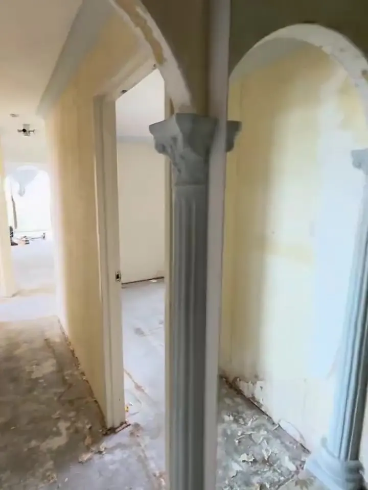 Before: hallway with yellowed walls and damaged floor