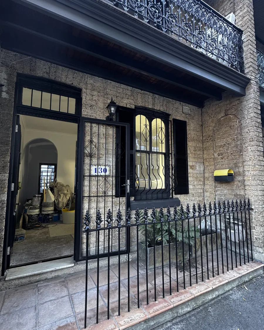Restored terrace house with black iron lace balcony and fence