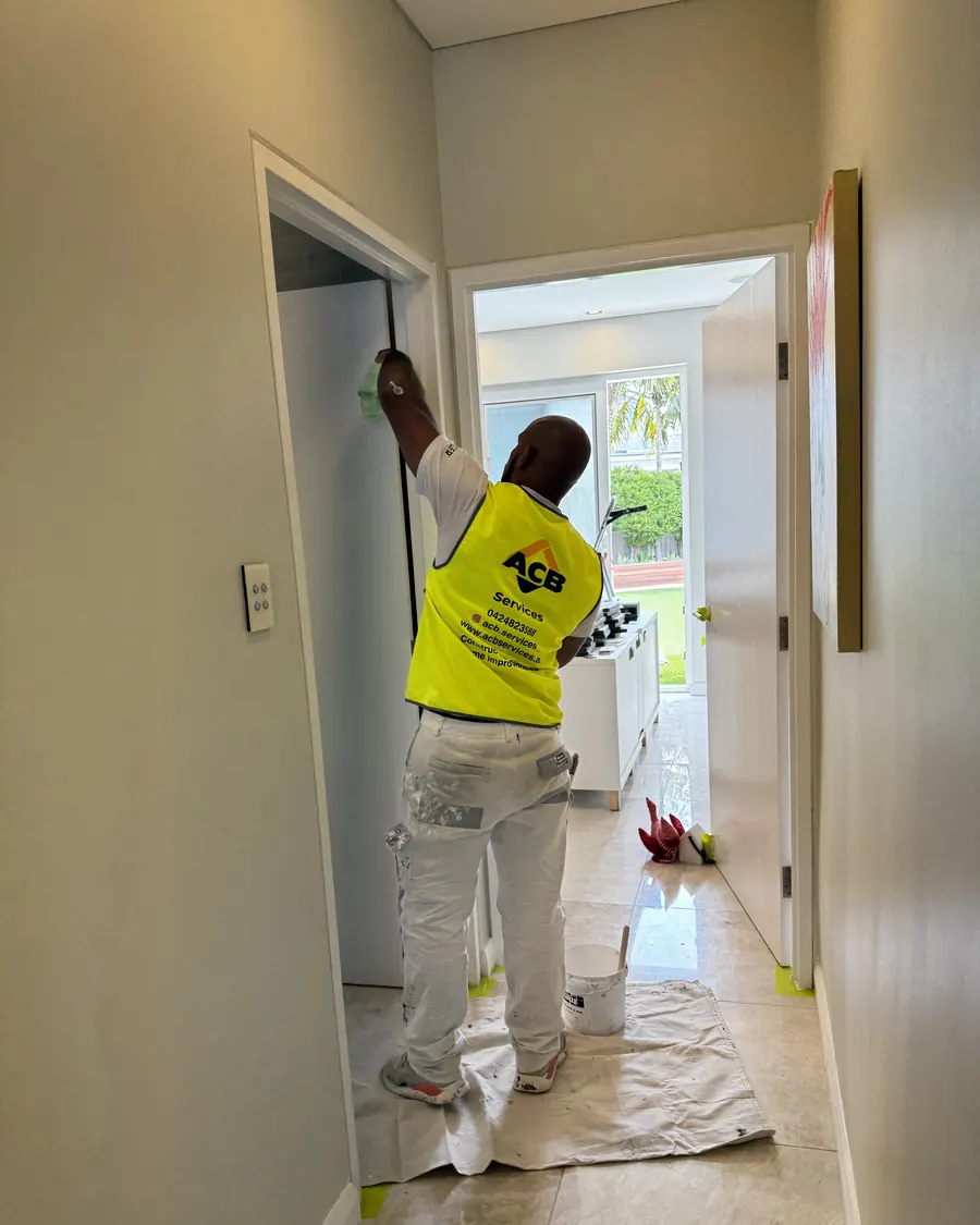 ACB painter cutting in a door frame in a hallway